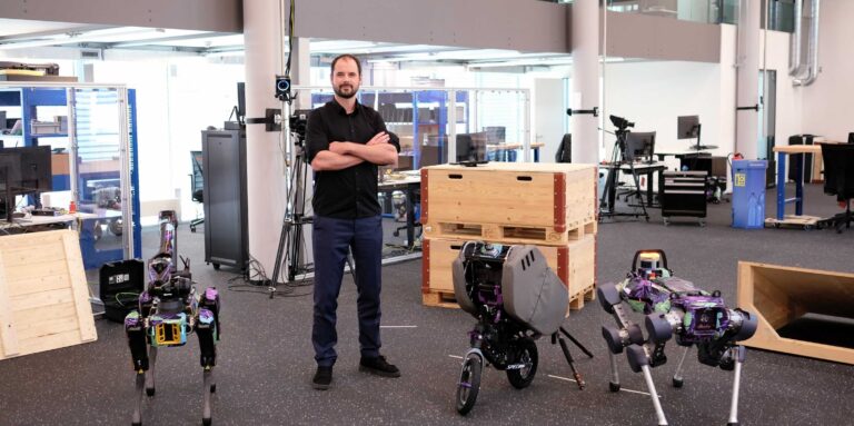 Marco Hutter stands near quadrupedal robots in an office
